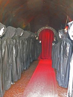 there is a long red carpet in the middle of this tunnel with black cloths on it