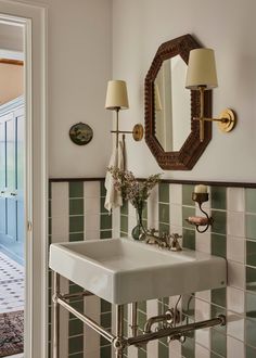 a white sink sitting under a bathroom mirror next to a wall mounted faucet