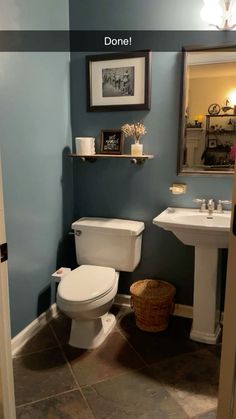 a white toilet sitting next to a sink in a bathroom under a framed picture on the wall