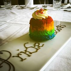 a rainbow cake on a white plate with the word happy birthday written on it