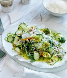 a white plate topped with cucumbers covered in parmesan cheese and sauce