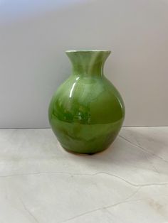 a green vase sitting on top of a white counter