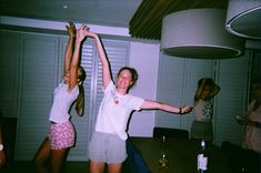 two young women standing in front of a table holding their arms up to the ceiling