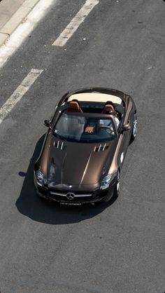 a brown sports car driving down the road