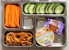 a lunch box with pretzels, carrots and cucumbers