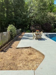 a backyard with a pool, table and chairs next to the fenced in area