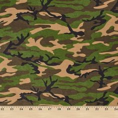 camouflage print fabric in green, brown and black colors with a ruler on the side