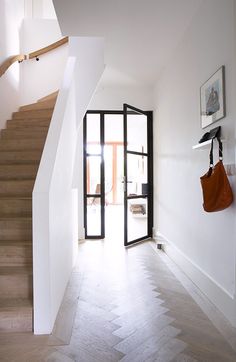 an open door leading to a hallway with wooden floors and handbags hanging on the wall