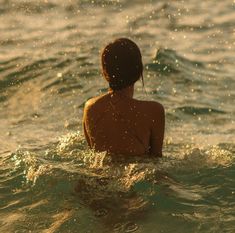 a woman sitting in the water with her back to the camera