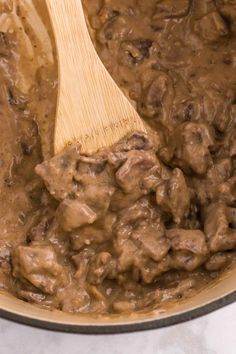 a wooden spoon stirring some food in a pot