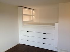 an empty room with white drawers and a bed in the corner on top of it