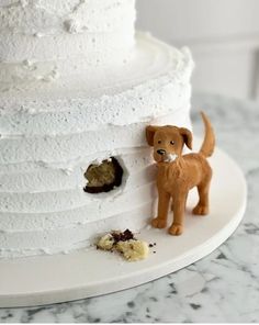 a white cake with a dog figurine next to it