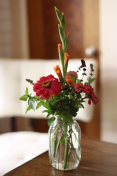 a vase filled with red flowers on top of a wooden table