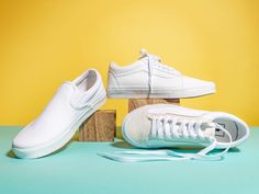 two pairs of white tennis shoes sitting next to each other on top of a wooden block