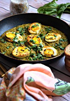 a skillet filled with eggs and spinach on top of a table next to bread