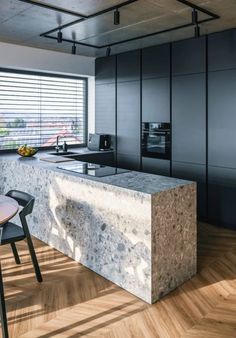 a modern kitchen with marble counter tops and black cabinets, along with an island in the middle