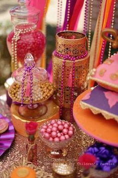 a table topped with lots of candy and candies covered in pink, orange and gold