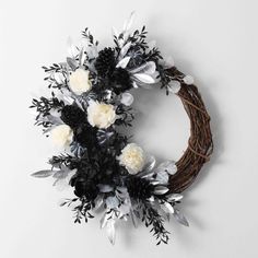 a wreath with white and black flowers hanging on the wall next to a planter