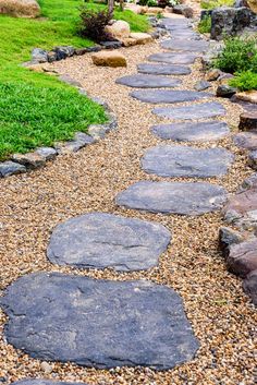 a stone path in the middle of a garden with grass and rocks on both sides