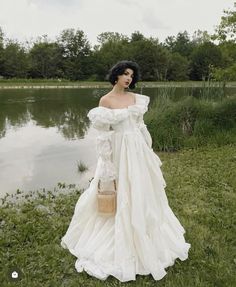 a woman in a white dress standing next to a lake