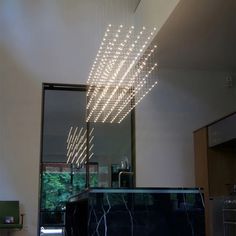 a modern chandelier hanging from the ceiling above a counter in a room with large windows