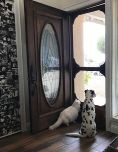 two dalmatian dogs sitting in front of a door