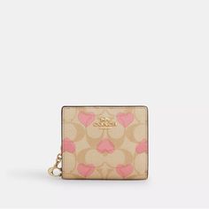 a small wallet with hearts on the front and pink linings, sitting on a white surface