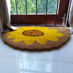 a door mat with a sunflower on it in front of a window and curtains