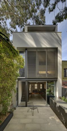 the house is surrounded by trees and has sliding glass doors that open up to let in light