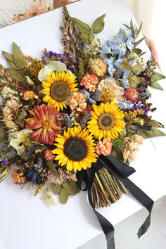 a bouquet of sunflowers and other flowers on a white box with black ribbon