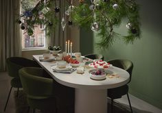 a dining room table with plates and cups on it, surrounded by greenery hanging from the ceiling