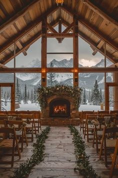 the inside of a building decorated with greenery and lit up by candle lights in front of a fireplace