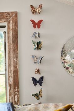 several butterflies are hanging on the wall next to a window with a mirror behind it