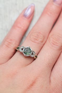 a woman's hand with an engagement ring on top of her finger and the other hand holding it