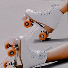 the legs and feet of a person riding roller skates with orange wheels on concrete