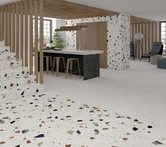 an open concept kitchen and living room with white flooring, wood slats on the walls