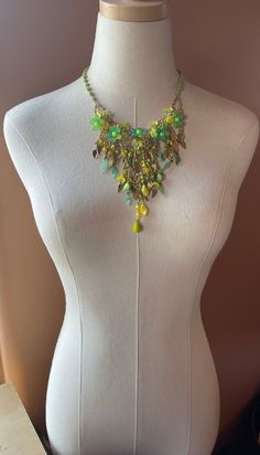 Colleen Toland Handmade Necklace circa late 90s.  This incredible necklace is made in stunning bright colors of green and yellow and gold.  The flowers are hand painted resin and are beaded together with glass seed beads.  The fringing is done with various uniquely shaped glass beads and metal and glass leaves that are rare to find today.  The necklace is wire wrapped with a square, matt green glass bead. The closure is a secure lobster claw with a signed metal tag so as it can be verified an original Colleen Toland work. The works shown in this shop are vintage Colleen Toland from past collections and they are the last of these pieces from Colleen's archive.  They are no longer in production and will not be remade.  They are not pre-owned and have never been worn.  They come with a certif Green Costume Jewelry Beaded Necklace, Yellow Beaded Dangle Necklaces, Bohemian Green Beaded Chain Jewelry, Green Dangle Jewelry With Colorful Beads, Green Colorful Dangle Jewelry, Green Dangle Costume Jewelry, Green Costume Jewelry Necklace, Yellow Beaded Costume Jewelry Necklace, Green Beaded Necklace With Dangling Beads For Party