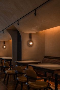 a row of tables and chairs in a room with lights hanging from the ceiling above them