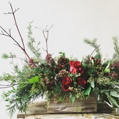 a wooden box filled with red flowers and greenery