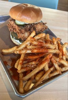 a chicken sandwich and french fries are on a metal tray, ready to be eaten