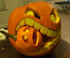 a carved pumpkin with the word e carved into it's face and mouth, sitting on a table