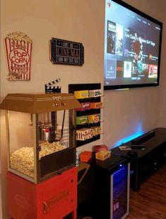 a tv mounted to the side of a wall next to a shelf filled with popcorn