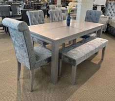 a dining room table and chairs with blue upholstered backrests in a store