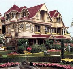 a large house with many windows and lots of flowers in front of the yard area