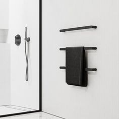 a black towel hanging on the side of a white wall next to a shower head