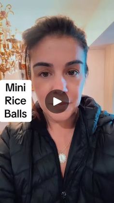 a woman in a black jacket is holding her hands up to her face and has the words mini rice balls written on it