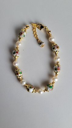 This bracelet is made of round white Cloisonné' beads, white Freshwater pearls and gold plated beads and findings. It has a 1" extension with a beaded drop making it adjustable. It has a lobster claw clasp.  Cloisonné is the technique of creating designs on metal vessels (cloisons) with colored-glass paste placed within enclosures made of copper or bronze wires, which have been bent or hammered into the desired pattern.  Custom Orders are always welcome! Ask about free sizing. White Pearl Beaded Bracelets With 8mm Beads, Adjustable White Pearl Rosary Bracelet, White Beaded Pearl Bracelet With Round Beads, White Beaded Bracelets With Pearl Drop, White Round Beaded Pearl Bracelet, White Beaded Pearl Bracelet, Elegant White Pearl Bracelet With Colorful Beads, White Pearl Bracelet With Spacer Beads For Wedding, White Gold Beads Bracelet