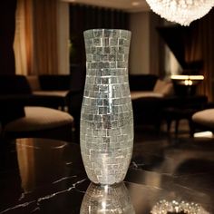 a glass vase sitting on top of a table in front of a chandelier