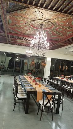 the dining room is set with long tables and chairs, chandelier hanging from the ceiling