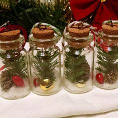 four glass jars filled with pine cones and christmas decorations